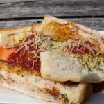 Toasted bread slices topped with tomato sauce, cheese, and herbs on a white plate.