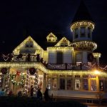 Victorian house decorated with bright Christmas lights at night.