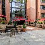 Outdoor patio area with tables, umbrellas, and brick building facade at Laurea.