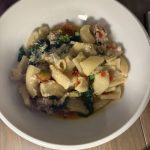 Pasta dish with ground meat, vegetables, and cheese served in a white bowl.
