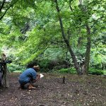 Hiker with map explores a dense, lush green forest trail.
