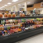Refrigerated display case stocked with various drinks, snacks, and condiments in a grocery store aisle.