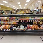 Grocery store aisle stocked with various beverages, snacks, and packaged goods on shelves.