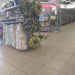 Floral display and clothing rack in a brightly lit retail store aisle.
