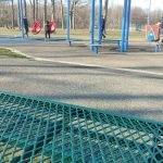 Outdoor playground with a red and blue shade structure under a clear sky.