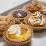 Assortment of mini tarts and muffins on a metal baking tray.