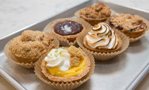 Assortment of mini tarts and muffins on a metal baking tray.
