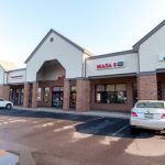 Strip mall with businesses including Chuckles Pizza & Restaurant on a sunny day.