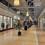Interior view of a modern shopping mall walkway with storefronts like Black Market.