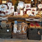 Holiday decor display featuring plates, candles, baskets, and rustic winter goods.