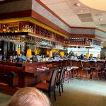 Upscale bar interior with extensive liquor shelves, polished wood, and ambient lighting.