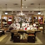 Holiday-themed retail display featuring rustic decor, ornaments, and seasonal goods in a bright store.