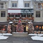 Snow-covered street in front of a hotel with festive Christmas decorations.