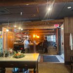 Restaurant interior showing a bar area and warm, rustic dining space.