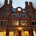 Red brick building facade with multiple windows and a clock above the entrance.