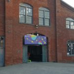 Red brick building entrance with "Trenton Circus Squad" sign and large windows.