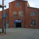 Brick building with arched windows and a central entrance, likely an old theater or venue.