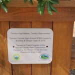 Plaque on a wooden bench honoring Trenton High School's STEM Academy and park funding.