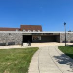 Mercer County Skating Center building with a paved walkway leading toward the entrance under a clear blue sky.