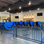 Interior view of a modern, spacious seating area with blue dividers and retail storefronts in the background.