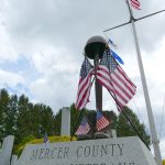 Vietnam Veterans Memorial statue in Mercer County, featuring American flags under a cloudy sky.