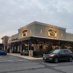 Bonfish Grille restaurant exterior at dusk with parked cars in the foreground.