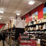Wine store aisle with shelves stocked high, featuring a display of various wine bottles.