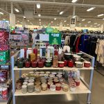 Display table filled with various craft supplies, beads, and small containers in a retail store.