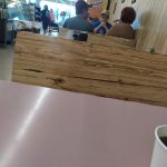 Wooden counter with people standing behind it in a bright retail setting.