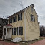 Yellow clapboard historic house under a cloudy, overcast sky.