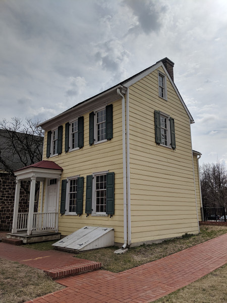 Yellow clapboard historic house under a cloudy, overcast sky.