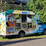 Colorful Kona Ice food truck parked outdoors on a sunny day.