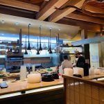 Rustic kitchen interior with chefs working behind a long wooden counter.