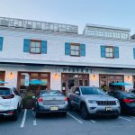 Modern storefront with blue shutters, cars parked in front of "Mistral" restaurant.