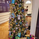 Decorated Christmas tree in a well-lit, formal room with historical displays.
