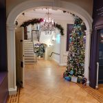 Grand foyer with archway, staircase, and a decorated Christmas tree.
