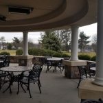 Outdoor patio dining area under a covered pavilion with tables and chairs.