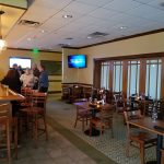 Restaurant interior with dining area, wooden tables, and warm lighting.