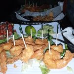 Fried shrimp and golden-brown appetizers served on a white platter with fresh lettuce.
