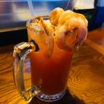 Spicy shrimp cocktail in a glass mug, garnished with seasoned shrimp.