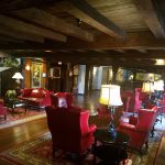 Rustic lodge interior with dark wood beams, comfortable red seating, and warm lighting.