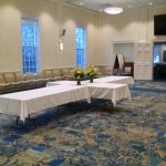 Conference room setup with tables, chairs, and floral arrangements for an event.