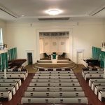 Interior view of a church sanctuary with pews, altar, and high ceilings.