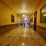 Long, ornate hallway with tiled floor and warm yellow walls.