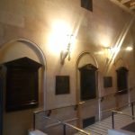 Grand interior hallway with high ceilings, arched alcoves, and ornate lighting.