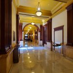 Grand, well-lit hallway with marble floors and tall columns in a classical interior.