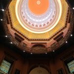Ornate, domed ceiling of a grand interior space with warm lighting.
