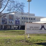 New Jersey State Museum building with large exterior art panels under a bright blue sky.