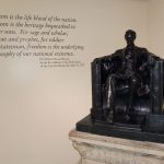 Bronze statue of a seated man next to text quoting Lincoln's on freedom.