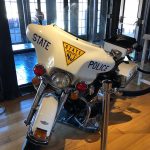 White police motorcycle with "STATE POLICE NJ" markings displayed indoors.